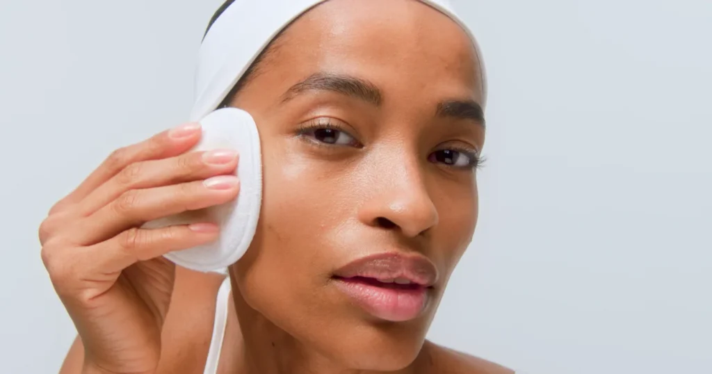 Top 5 Skincare Tips Before Applying Makeup woman applying toner to face with cotton pad — balancing skin pH.
