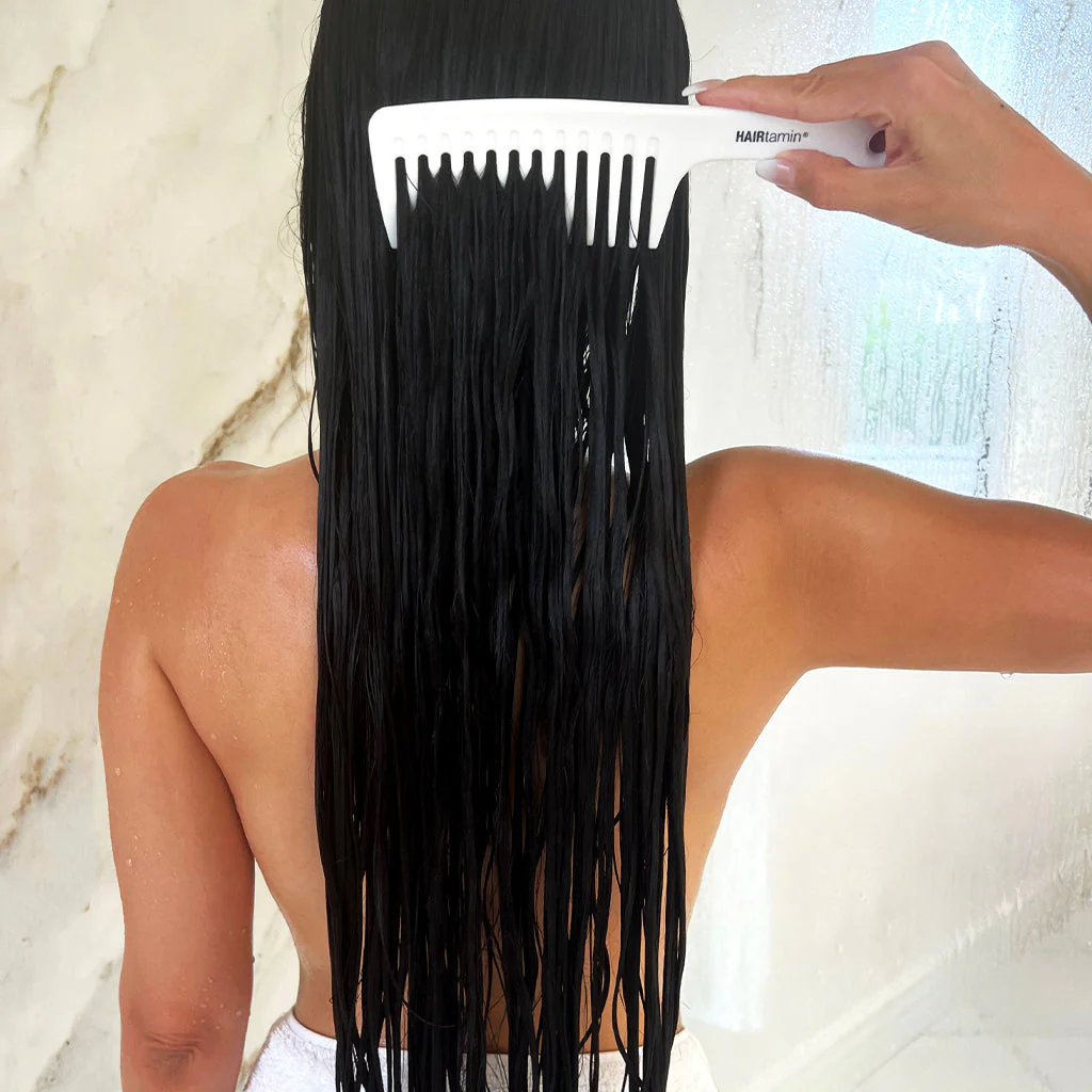 Wide-tooth comb gently detangling wet hair โ Step 4 in haircare routine.