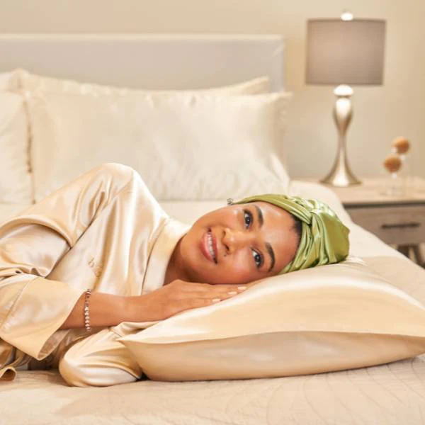 Woman sleeping on silk pillow with hair wrappedโnight haircare routine step.