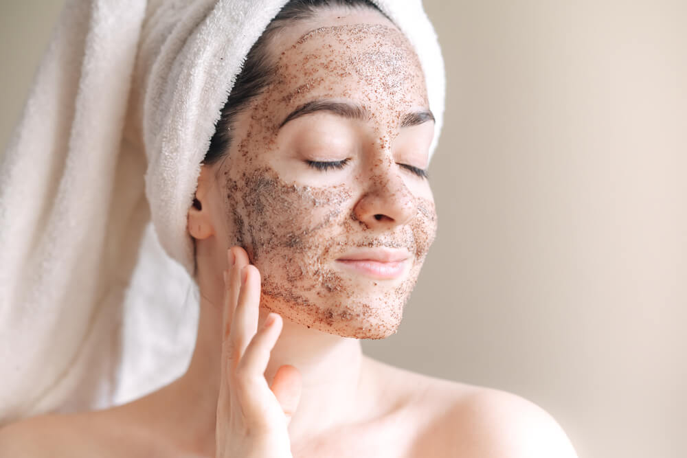 Top 5 Skincare Tips Before Applying Makeup Woman exfoliating her face with a scrub — prepping skin for flawless makeup.
