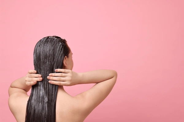 Woman applying deep conditioner to wet hair โ deep conditioning step in haircare routine